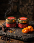 Chipotle and Habanero chili flakes jars on slate with dried chilies and smoke